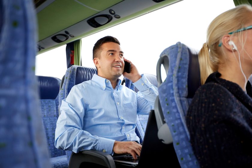 transport, tourism, business trip and people concept - smiling man with smartphone and laptop calling in travel bus